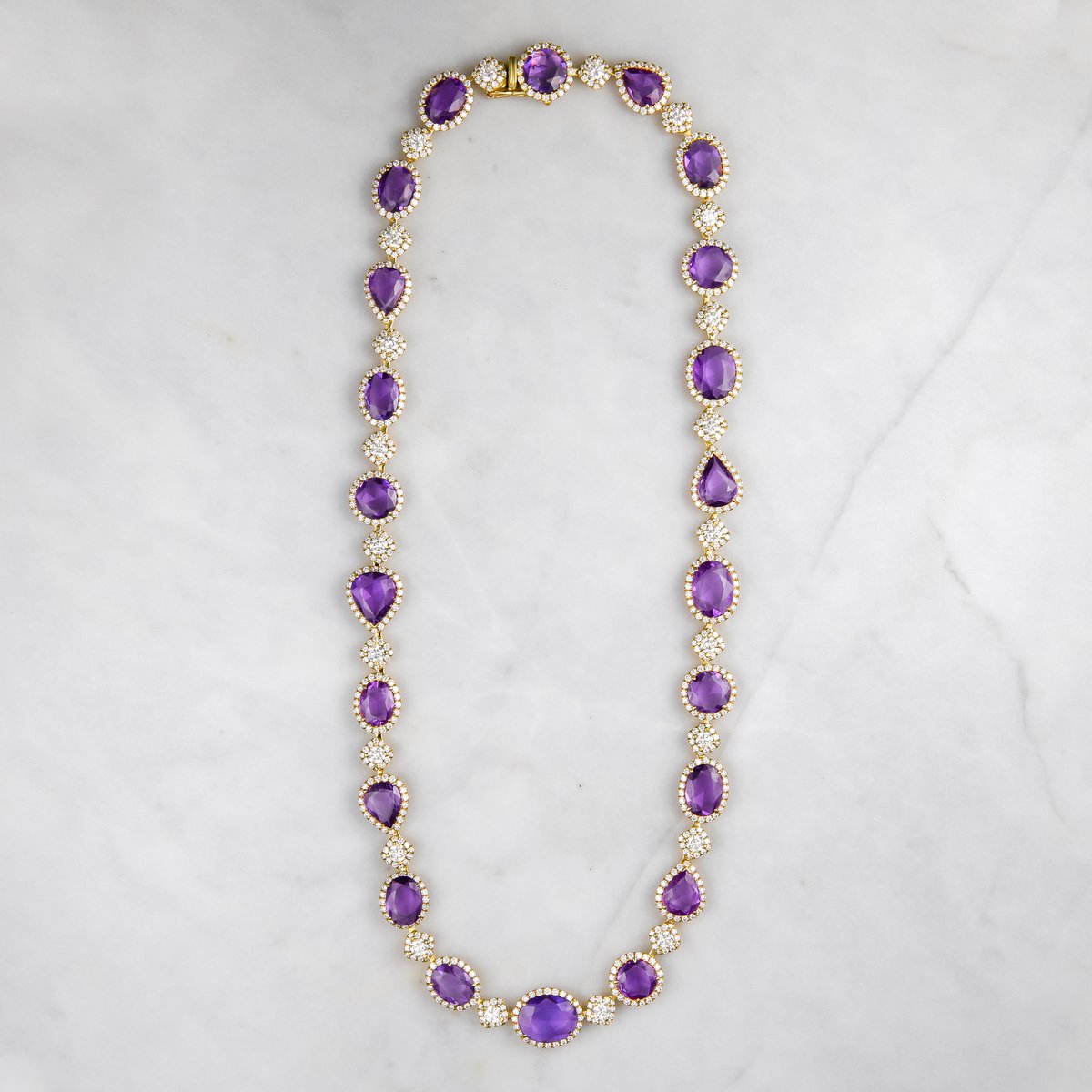 Custom necklace of bezel-set pear and oval amethysts with diamond links in yellow gold