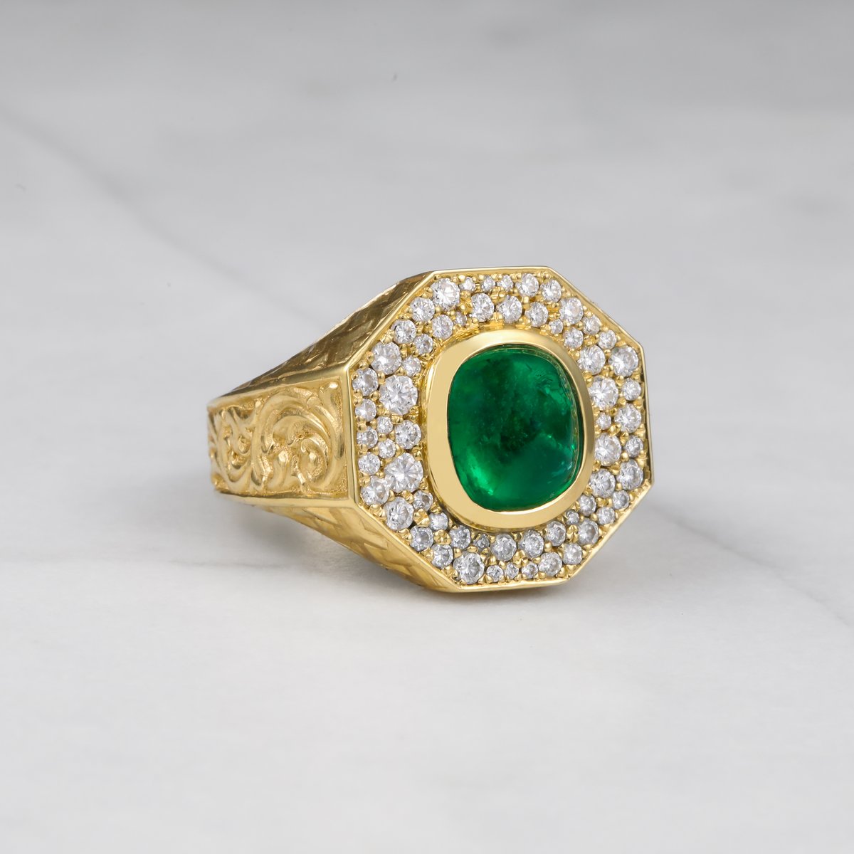 Custom octagonal yellow gold signet ring with a cabochon emerald, diamond halo and engraved shoulders