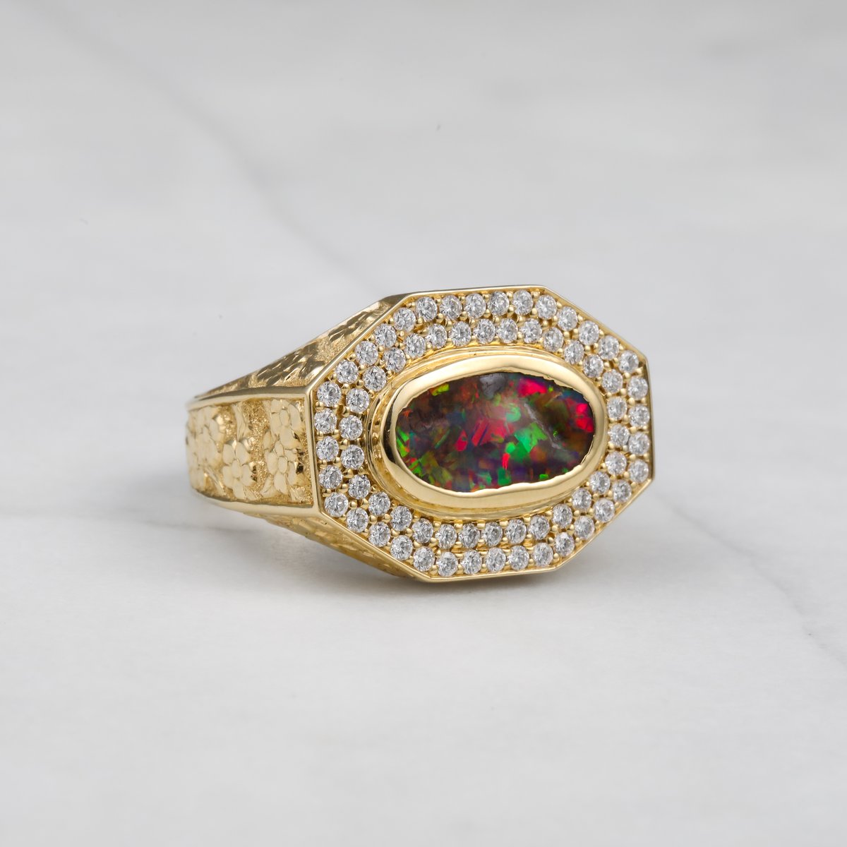 Custom yellow gold signet ring with a black opal center, diamond halo and engraved shoulders